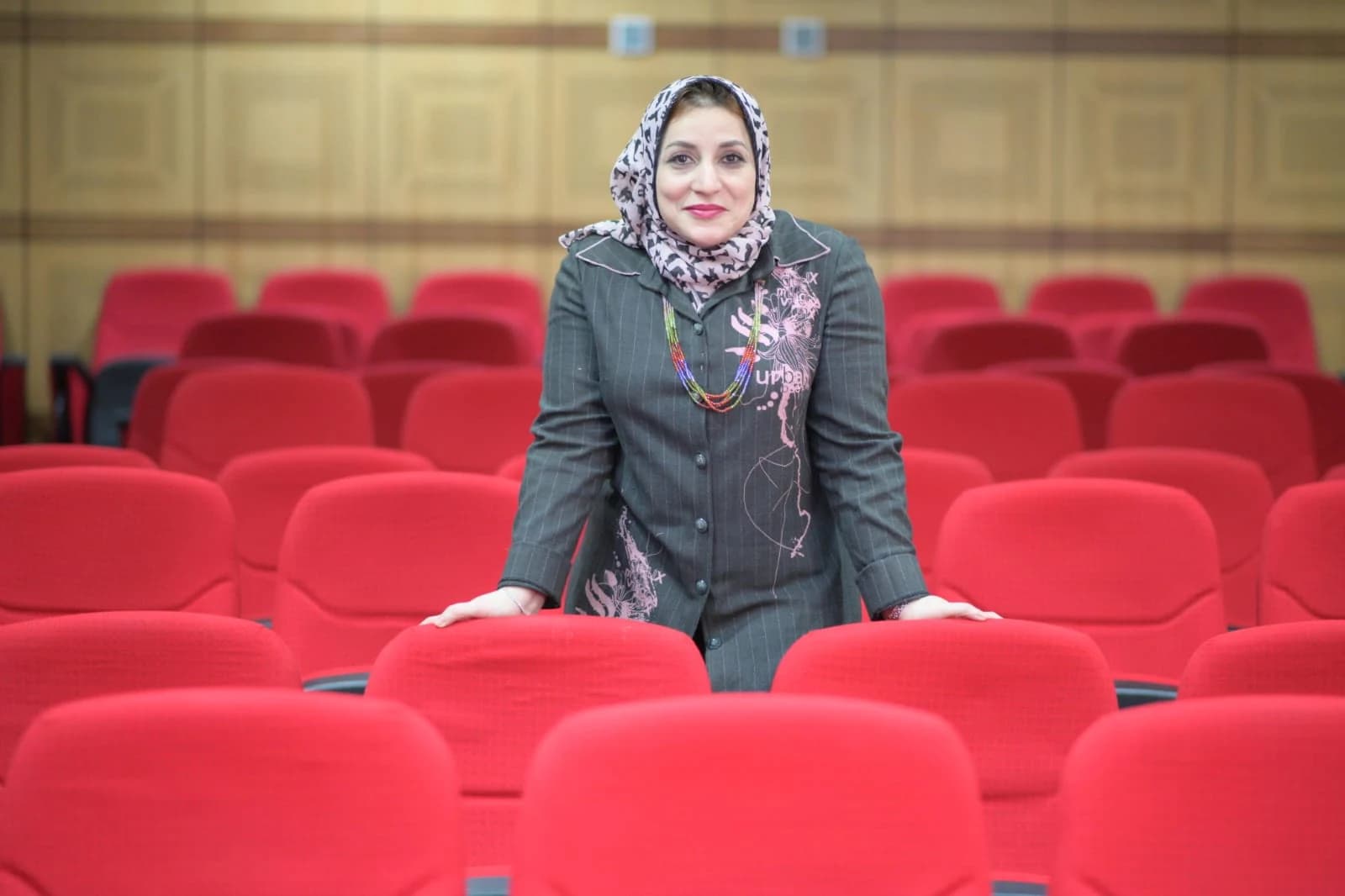 د. منال الدغار واقفة بين مقاعد قاعة محاضرات
